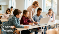 A teacher and young students looking at a laptop in a classroom