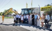 A group of people posed in front of a large construction vehicle