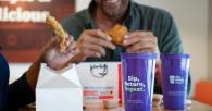 People eating chicken, purple cups in the foreground