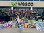 A group standing behind new toys, in front of a Wesco building
