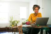 A person in a home setting looking at a laptop.