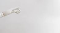 a white robotic hand from the left side of the screen, a white backdrop