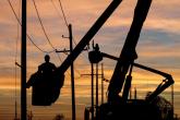 silhouette of someone working on a powerline