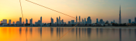 A city skyline at sunset, a body of water in front.