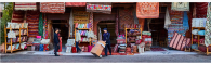 A person delivering boxes at a shop with colorful textiles hanging.