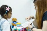 A caregiver works one-on-one with a young child during a speech therapy session.