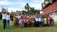 A group of youth and adults posed outside with arms up.