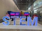 Two people standing behind large letters "S T E M".
