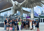 A smiling group posing in front of an eagle sculpture