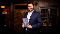 Mike Hower holding his new book