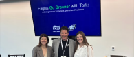 Three people standing in front of presentation. Screen behind says, "Eagles Go Greener with Tork"