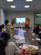 A person presenting to a conference room of others seated.