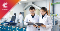 Two people in white coats looking at clipboard together