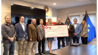 A small group standing together, holding an oversized check from KeyBank