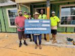Wesco and Habitat for Humanity Team Members shown with $35,000 grant check on a building site.