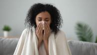 A person shown with a tissue and a blanket over their shoulders.