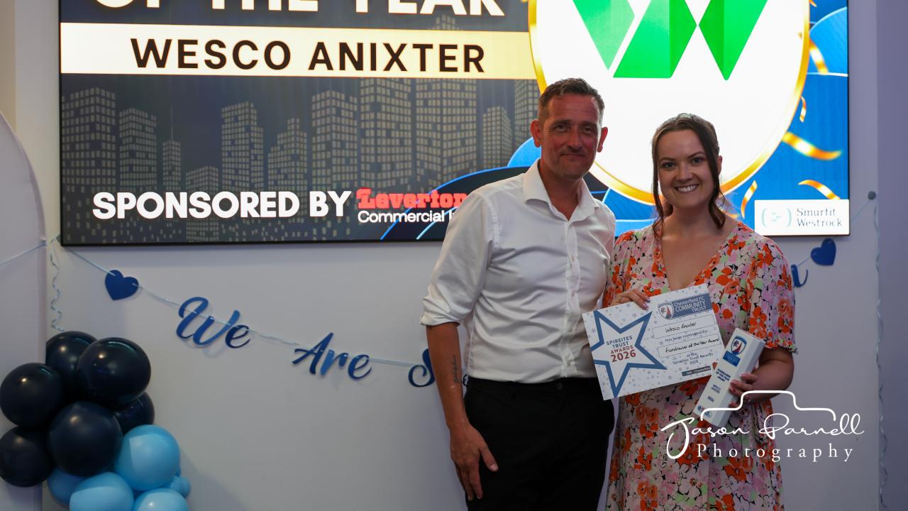 Man and woman standing in front of Wesco logo