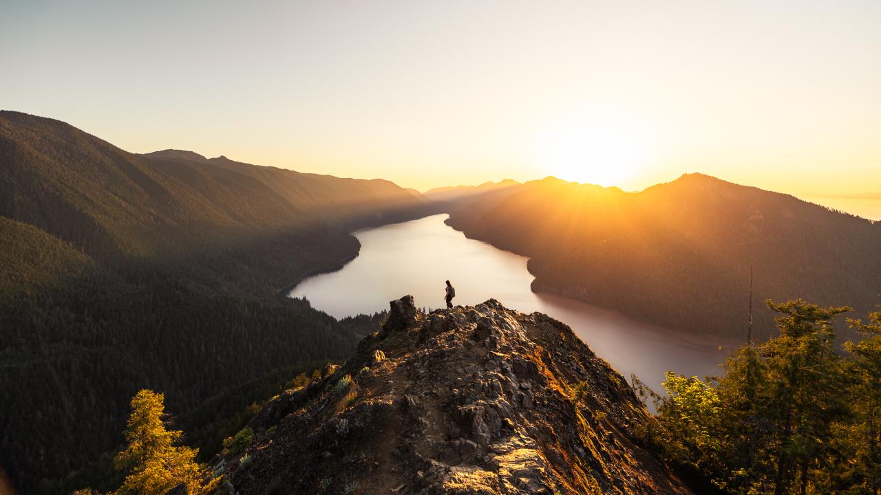 Aerial shot of someone hiking in the mountains high above a body of water