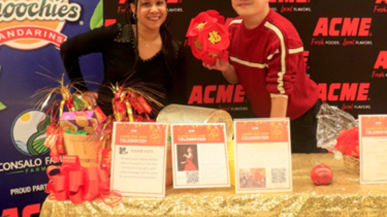 People posing at booth with "ACME" logo