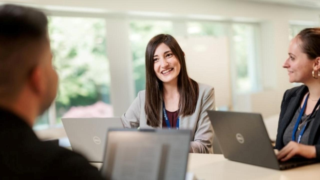 Group photo of employees working from laptops looking happy 