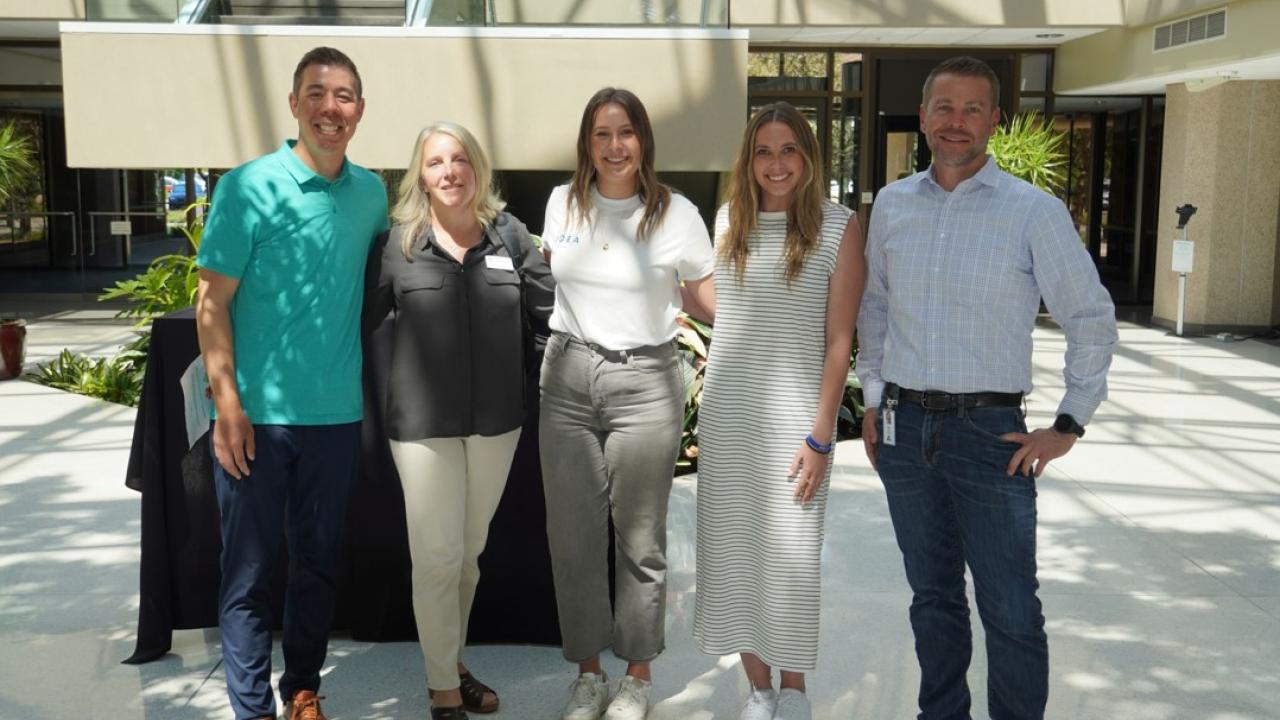 Five people posing for picture in office