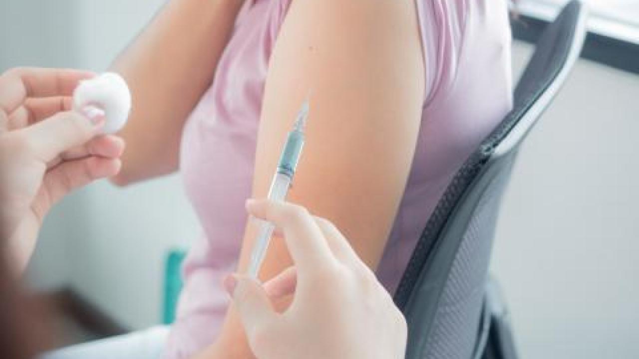 Pharmacist preparing to provide treatment to patient with an injection needle and cotton ball.