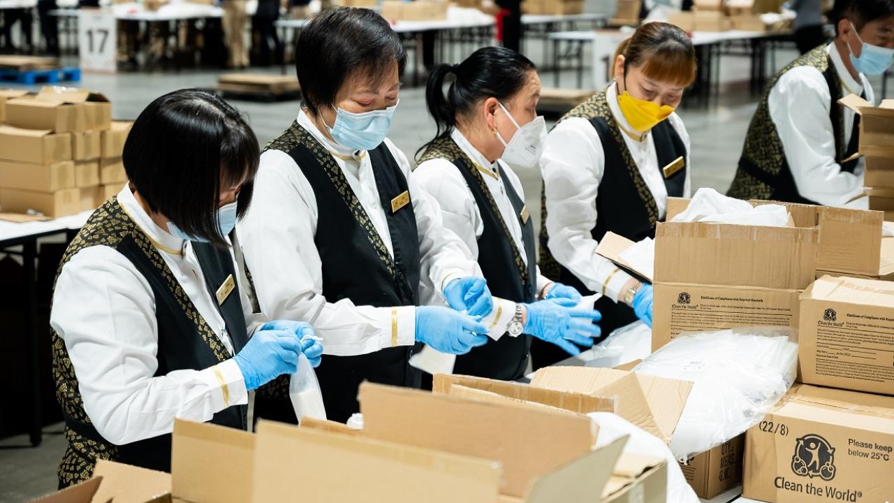 People in masks and gloves working with boxes on tables