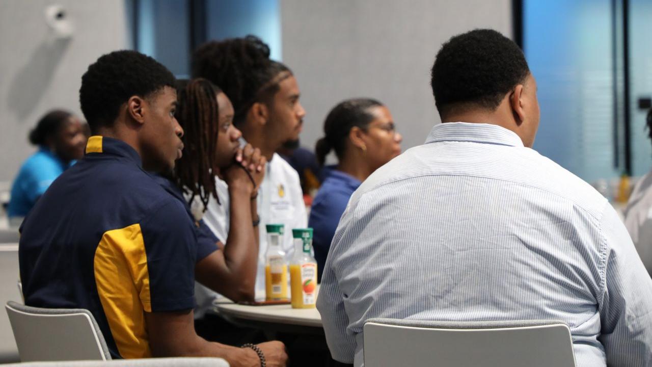 Students sat at a table looking towards the front of the room