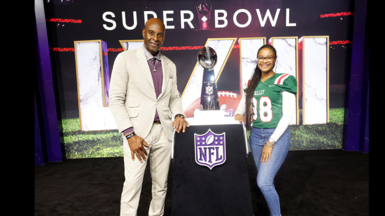 Two people stood near the super bowl trophy 