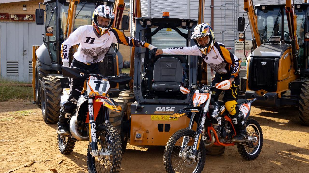 Two people on motorbikes fist bumping 