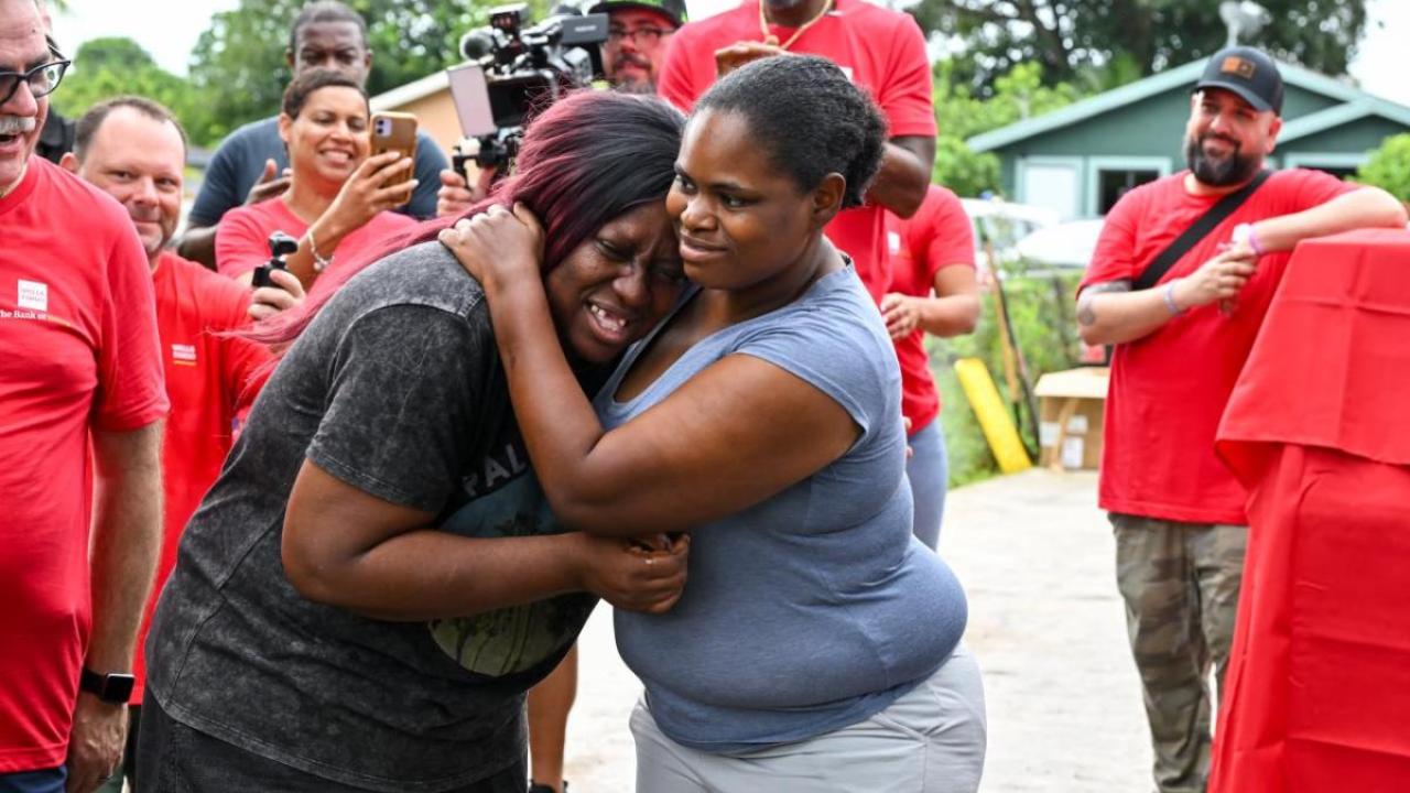 Two women hugging, surrounded by Wells Fargo Volunteers