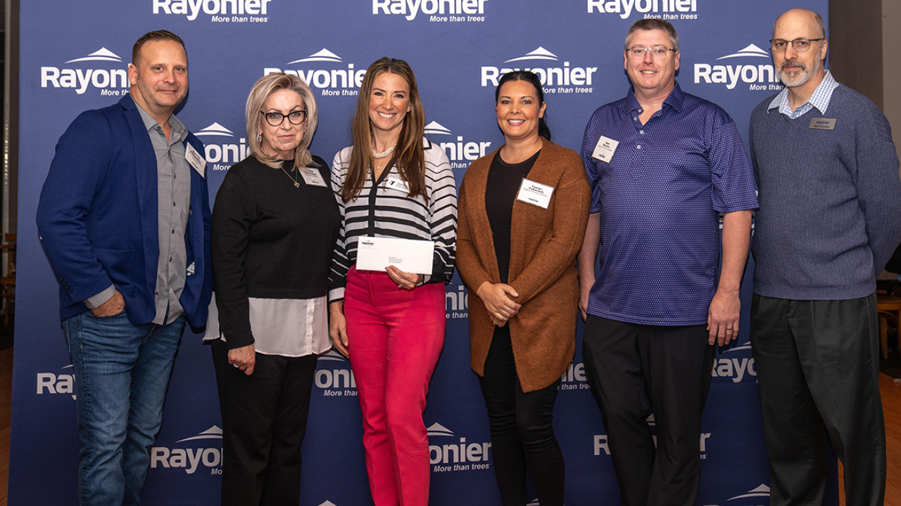 Six people standing together, one holding a check