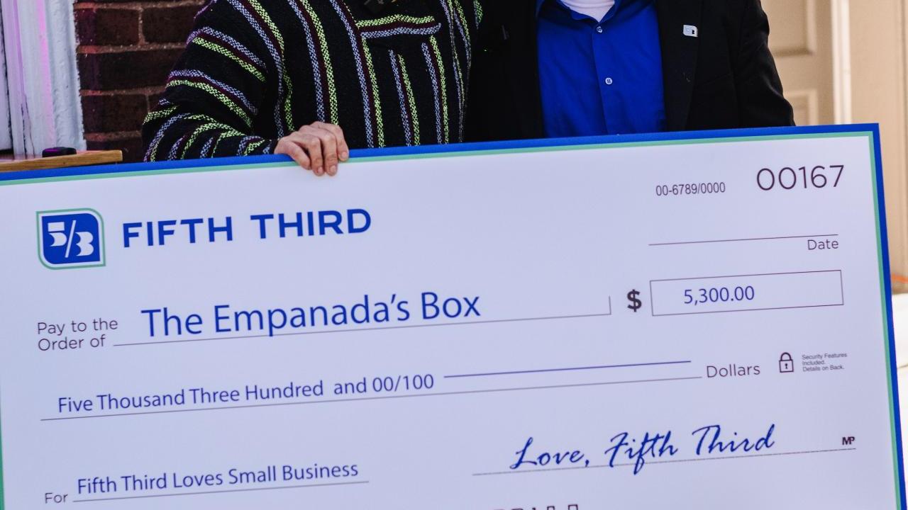 Two smiling people holding an oversized check