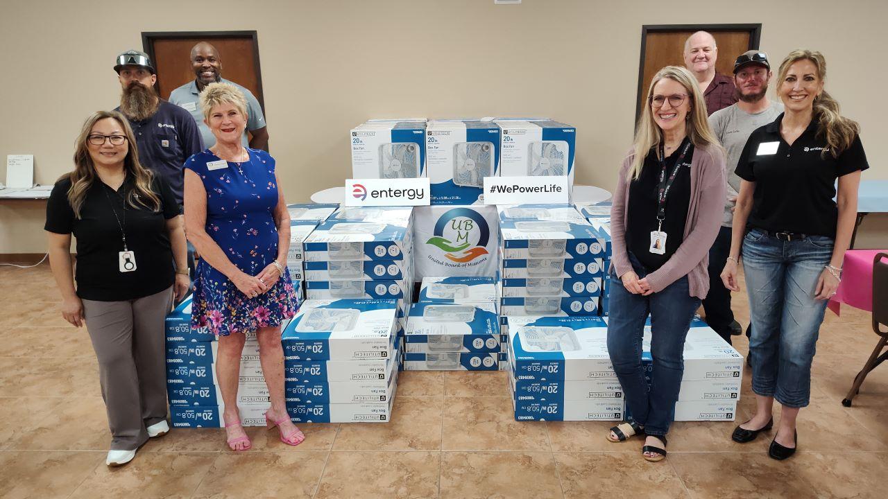 People standing next to stacks of new fans in boxes