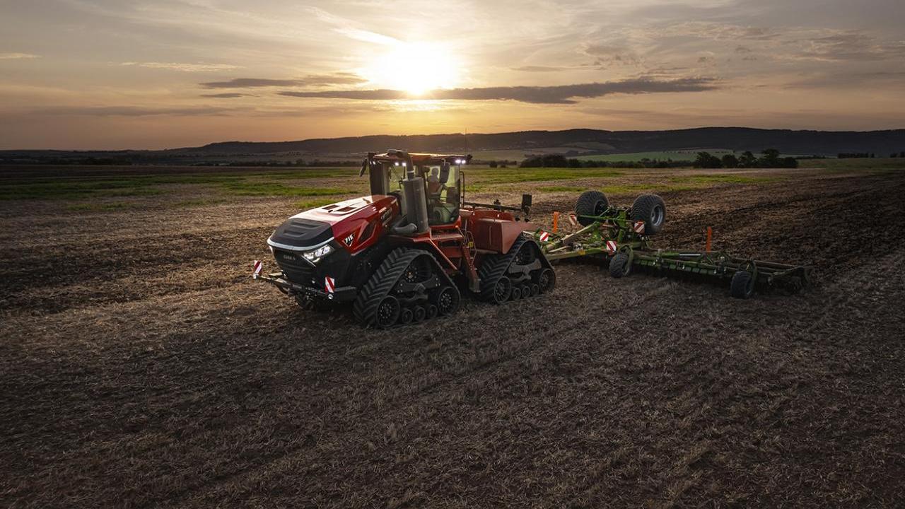 Red tractor on a field with a sunset behind it