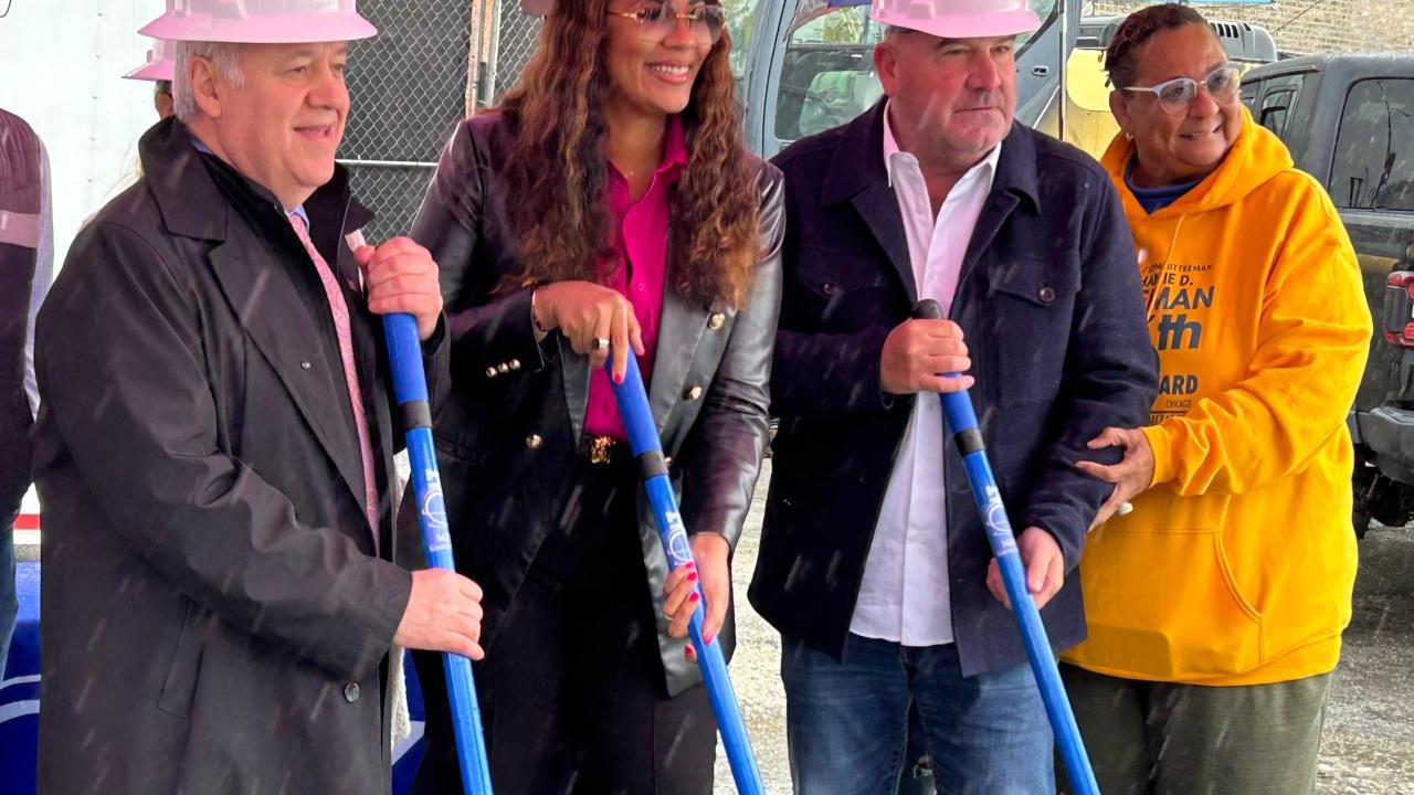 Four people standing together with shovels and hardhats in a breaking ground ceremony