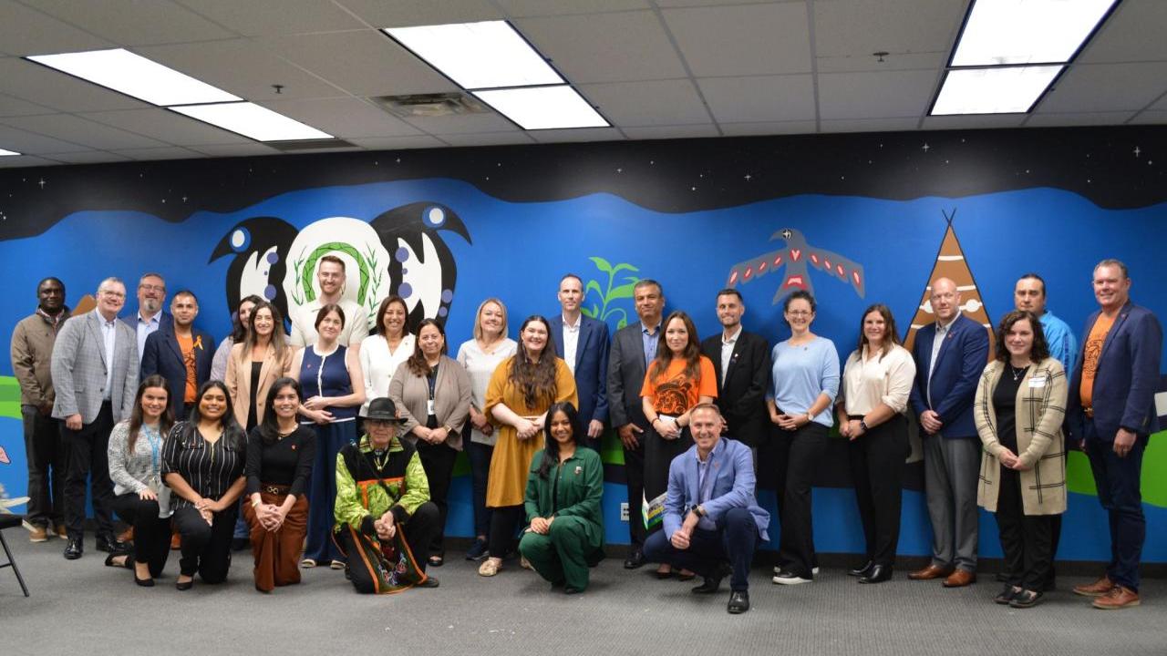 A group of people posing in front of a large mural