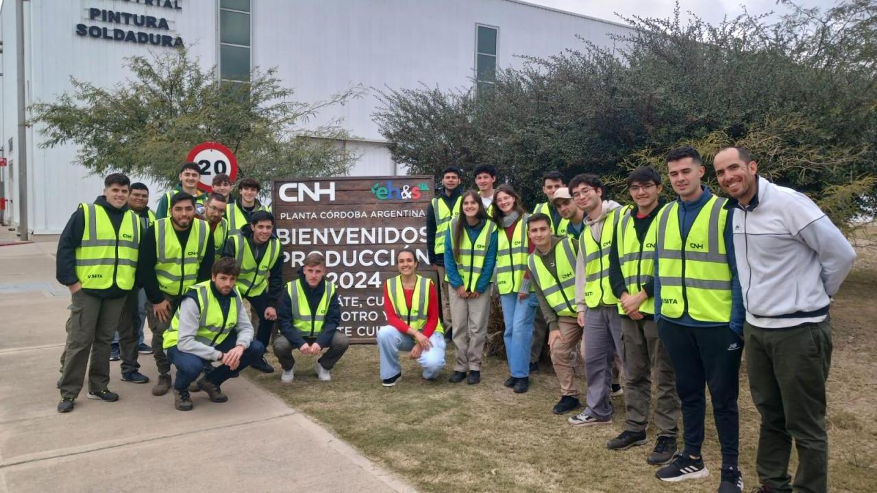 People in safety vests standing next to a sign for CNH