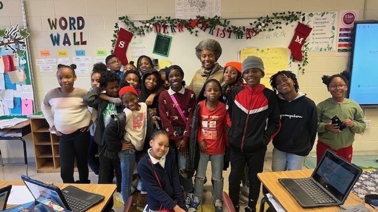 Students and teacher stand in front of classroom