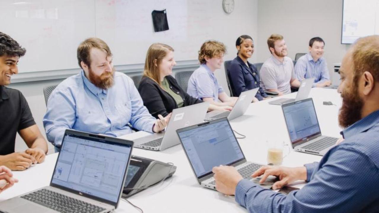 People sitting at a conference table working on laptops