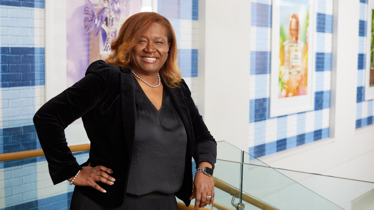 Kelie Charles smiles at the camera while standing at the top of a set of steps at the Bath & Body Works headquarters building in Columbus, Ohio.