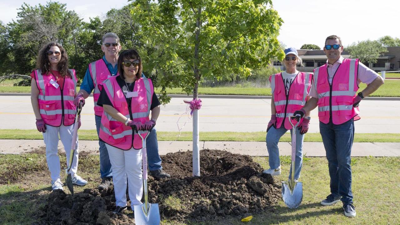 People in pink vests planting a tree