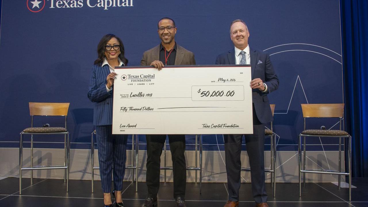Three people holding a large check
