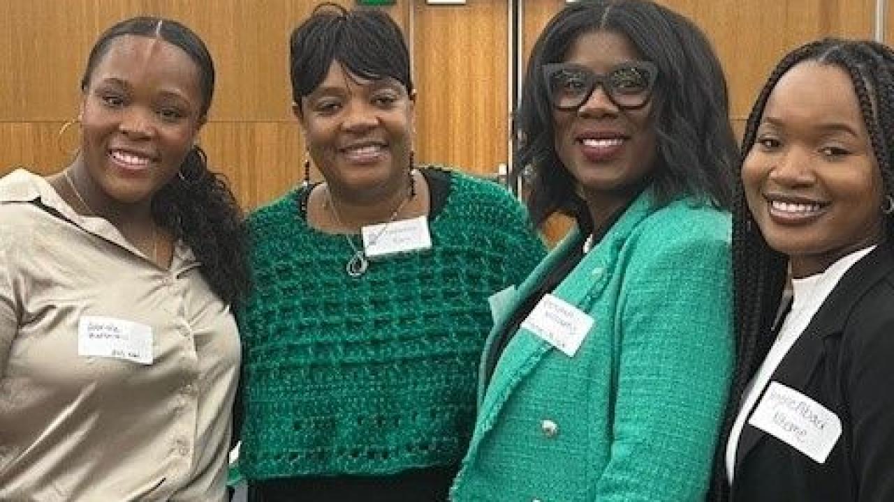 Four people stand together smiling