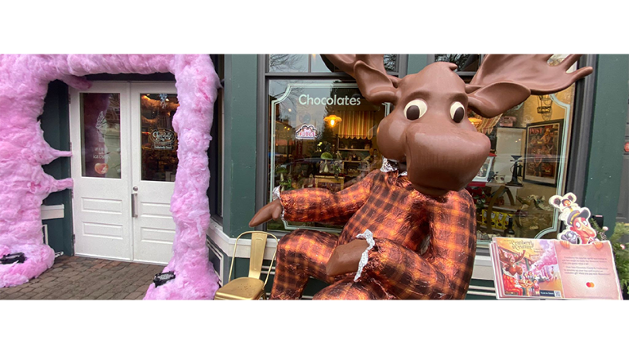 A giant chocolate moose "sitting" in front of a store