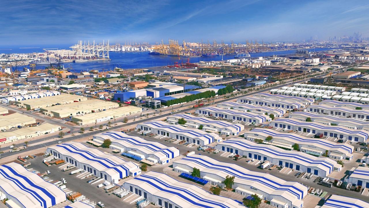 Aerial view of DP World’s Jebel Ali Free Zone in Dubai, showing expansive warehouses, logistics facilities, and the adjacent Jebel Ali Port with cranes and container ships along the waterfront.