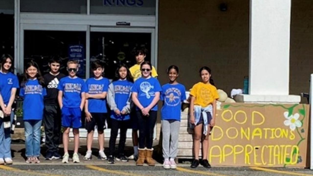 A group of people standing in front of a building with sign that reads "Food Donations Appreciated"