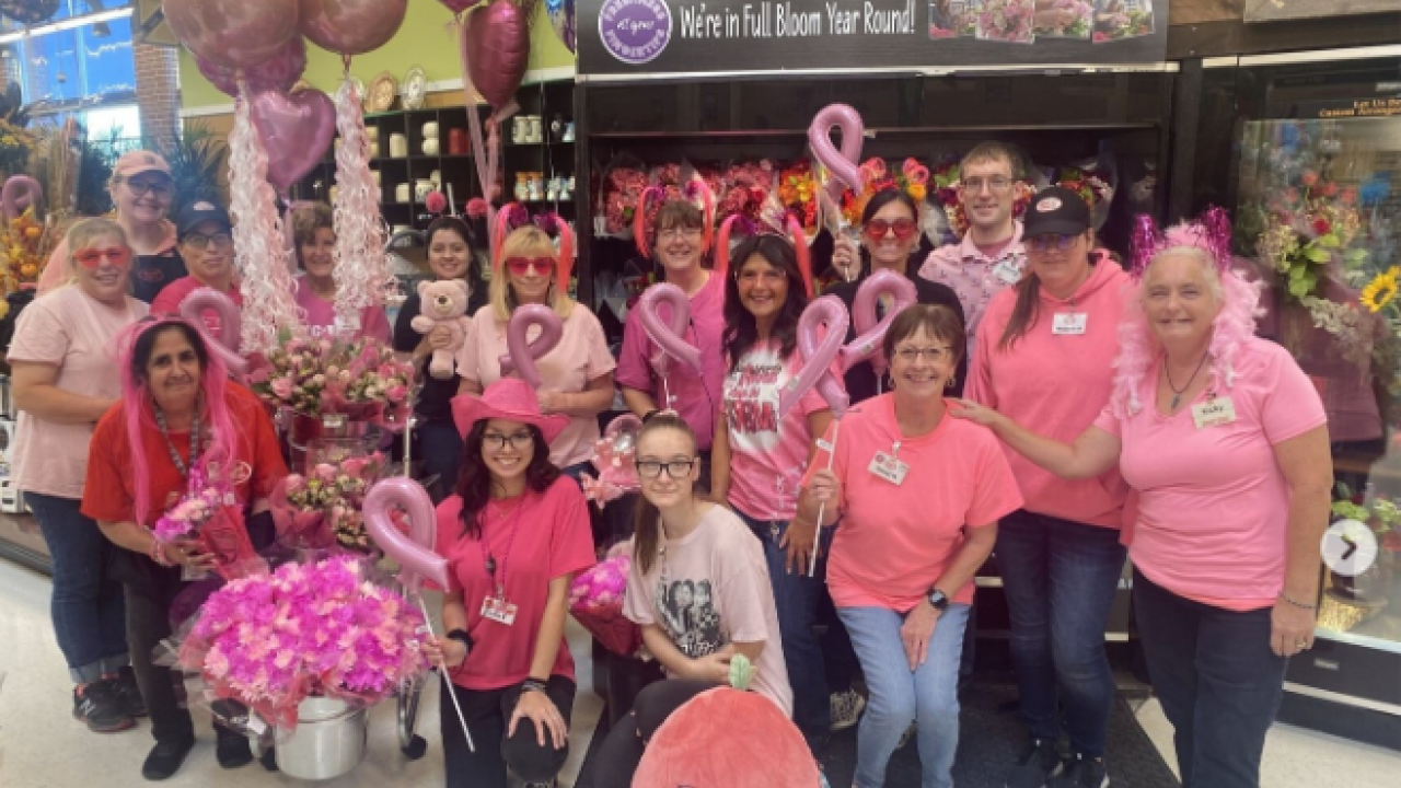 Group of people in pink shirts posing in a Jewel-Osco store