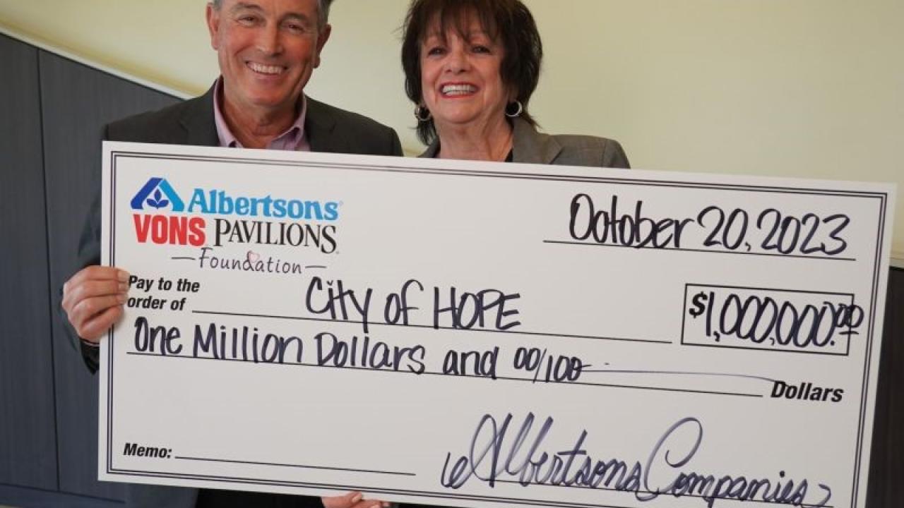Two people holding a check to City of Hope