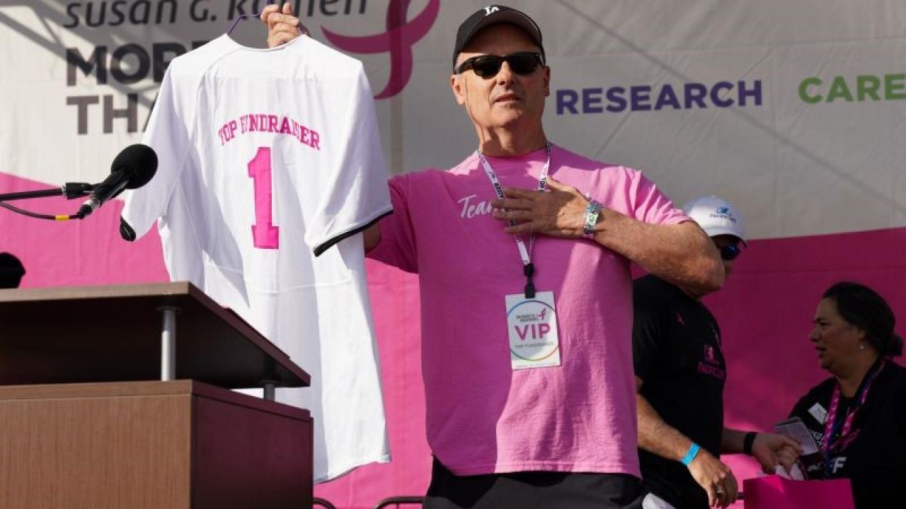 Man holding t-shirt jersey with #1 and Top Fundraiser on back.